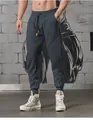 Detailed view of men's charcoal grey athletic joggers with cuffed ankles on model. - Iron Grey