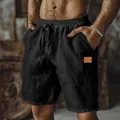 Close-up detail of black cotton linen shorts featuring drawstring waist and a side patch - S / Bottoms / Black