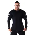 Detailed view of athletic fit long-sleeve gym shirt on a professional male muscle model - M / Tops / Black Type 1