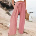 Detail shot of pink wide-leg drawstring pants worn on a sunny sandy beach setting. - Peach
