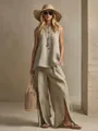 Stylish woman in a beige sleeveless linen top and split-hem wide-leg pants with straw hat - Khaki