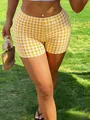 Close-up of women's Y2K yellow gingham slim fit shorts in summer outdoor setting - S / Bottoms / Three-quarter Pants / Yellow Check