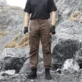Men's brown tactical cargo pants with multi-pockets in outdoor rocky terrain - Coffee