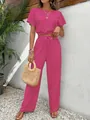 Detailopname van de elegante roze tweedelige set met getextureerde stof en wijde broek - Rozerood