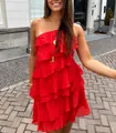 Detail van een levendige rode mini-jurk met ruches en één schouder in een zonnige straat - S / Rood