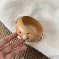 Detailaufnahme eines Retro-Holzarmreifens mit Goldnieten und weißen Perlenakzenten - Breiter Künstliche Perle Nieten Stil / Gold-Kaffee-Perle