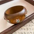 Makroansicht eines Vintage-Holzarmreifens mit silbernen Blumen und Türkisperlen - Silberne Pflaumen Türkis Dekoration / Dunkelbraun