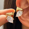 Close-up detail of a gold-tone twisted ear cuff featuring a large pear-cut cubic zirconia. - 1 Pair / Gold