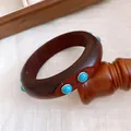 Nahaufnahme eines Vintage Holzarmreif mit türkisfarbenen Steinen auf einem Holzständer - Vintage Dickes Blaues Türkis Holz / Dunkelbraun-Blauer Türkis