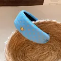 Detailed view of a light blue fabric wide headband with pink polka dots and gold button. - Blue Polka Dot / Blue