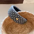 Macro view of grey polka dot fabric headband featuring a small gold-tone metal accent - Gray