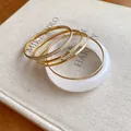 Detail of five-piece set with white resin bangle and gold-plated metal bracelets - Five-Piece Set / Gold-White