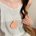Detail einer muschelförmigen magnetischen Brillenclip-Halskette aus Leder auf Kleid. - Halskette / Rosa
