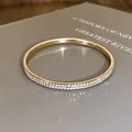 Detailopname van een goudkleurige ronde armband met twee rijen strassteentjes - Goud & Wit (AB Kleur)