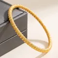 Macro view of elegant gold twisted titanium steel bangle displayed on a gray jewelry box - Twisted Style (46-E-6) / Gold