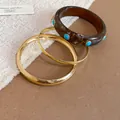 Detailansicht von gestapelten goldenen Armreifen und einem braunen Harzarmband - 8# (3-teiliges Set)