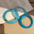 Nahaufnahme von drei blauen Harzarmreifen mit Marmormuster auf einem offenen Buch. - 24# (3-teiliges Set)