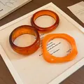 Detailansicht von vintage bernsteinfarbenen und orangefarbenen Harz-Armreifen auf Leinwand - 29# (3-teiliges Set)