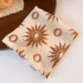 Close-up view of folded polyester square bandana with vintage sunburst print details. - Bohemian Celestial Sun Pattern Style / Coffee-Beige