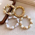 Primer plano de un set de 4 pulseras elásticas con cuentas doradas y de perlas - Pulsera - Dorado / Blanco