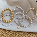 Close-up of elegant acrylic pearl and gold beaded bracelet set displayed on beige fabric - 6-Piece / Gold-White