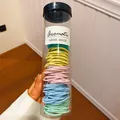 Detailweergave van kleurrijke haarelastiekjes in een transparante opbergkoker - Set van 100 / Roze-Blauw-Cyaan-Groen