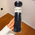Detailweergave van zwarte elastische haarelastiekjes in een doorzichtige koker. - Set van 100 / Zwart