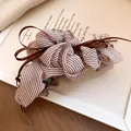 Close-up detail of a brown striped pleated fabric hair claw clip with satin ribbon tassel - Striped Pleated Bow Tassel Claw / Brown