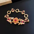 Detalle de una pulsera vintage dorada con diamantes de imitación rosas y mariposa - Pulsera Tono Dorado Rosa Rojo (HB6656)