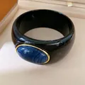 Close-up of a black resin bangle featuring a large blue marbled oval stone detail. - Geometric Open Style (35#)
