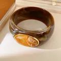 Macro view of a retro thick resin bangle featuring a marbled orange stone set in gold - Geometric Open Style (42#)