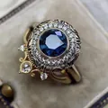 Detailed view of a vintage gold ring with a large blue sapphire-like gemstone and zircon halo - Size 5 / Gold Round Dark Blue Zirconia Style (CY908)
