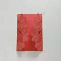Gros plan d'une carte d'invitation de mariage rouge découpée au laser avec fleurs - Rouge