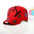 Close-up of a red graffiti baseball cap with black JOY print and star patterns - Kids / Red
