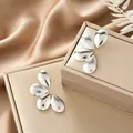 Elegant silver stainless steel irregular flower petal stud earrings on beige jewelry box - Brushed Petal Overlaid Style (E1323-B) / 1 Pair Pack / Steel
