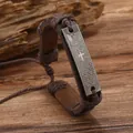 Nahaufnahme des gravierten Kreuzes und der Schrift auf dem braunen Vintage-Lederarmband - Kaffeebraun