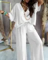 Detalle del elegante top blanco con cuello en V y el conjunto de pantalón ancho - Blanco