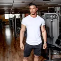 Professional male athlete in white high-stretch fitness T-shirt and black gym shorts - M / Tops / White Shoulder Print