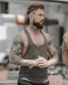 Muscular male model wearing a grey breathable elastic fitness tank top in a professional gym setting - M / Tops / Gray