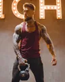 Detailed view of burgundy muscle fitness tank top on a tattooed model during workout - M / Tops / Red
