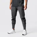 Close-up detail view of charcoal grey multi-pocket joggers on model with ribbed cuffs - S / Bottoms / Dark Gray