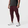 Detail view of men's burgundy cargo joggers with zipper pocket and tapered cuffs. - S / Bottoms / Burgundy
