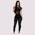Full view of model wearing black high waist ripped skinny jeans and a mesh crop top. - S / Bottoms / Black