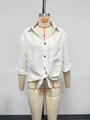 Close-up of a white linen-style short sleeve shirt with front tie-knot and V-neck detail. - S / Tops / White