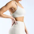 Detail view of seamless beige yoga bra with criss-cross back straps on model - Feather Beige