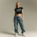 Model trägt personalisierbares schwarzes Crop-Top-T-Shirt und blaue Cargo-Jeans - Kundenspezifisches Modell 4