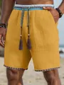 Close-up van gele heren strandshort met etnische kwastjes en getextureerde stof - M / Bottoms / Gembergeel