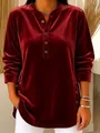 Detail of burgundy velvet long-sleeved top featuring elegant button accents on neckline. - Burgundy