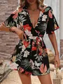 Detail of a tropical floral print romper with ruffled sleeves and wrap V-neck design - S / Black