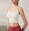 Detailed shot of a cream-colored sports bra with double thin straps on a fit model - Light Ivory White